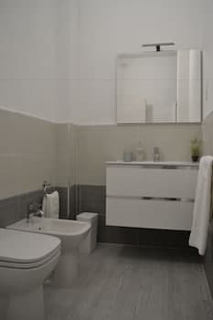 A modern bathroom with sleek white fixtures, gray tiled walls, and a minimalist design creates a serene atmosphere, ideal for travelers seeking a clean and stylish accommodation space.