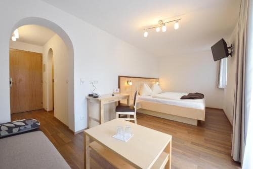 A cozy hotel room features a neatly made bed, wooden furnishings, and soft lighting, creating a welcoming atmosphere ideal for travelers seeking comfort and relaxation.