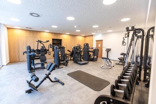 A well-lit indoor gym with various exercise machines and free weights offers a serene workout environment ideal for travelers seeking fitness amenities during their stay.