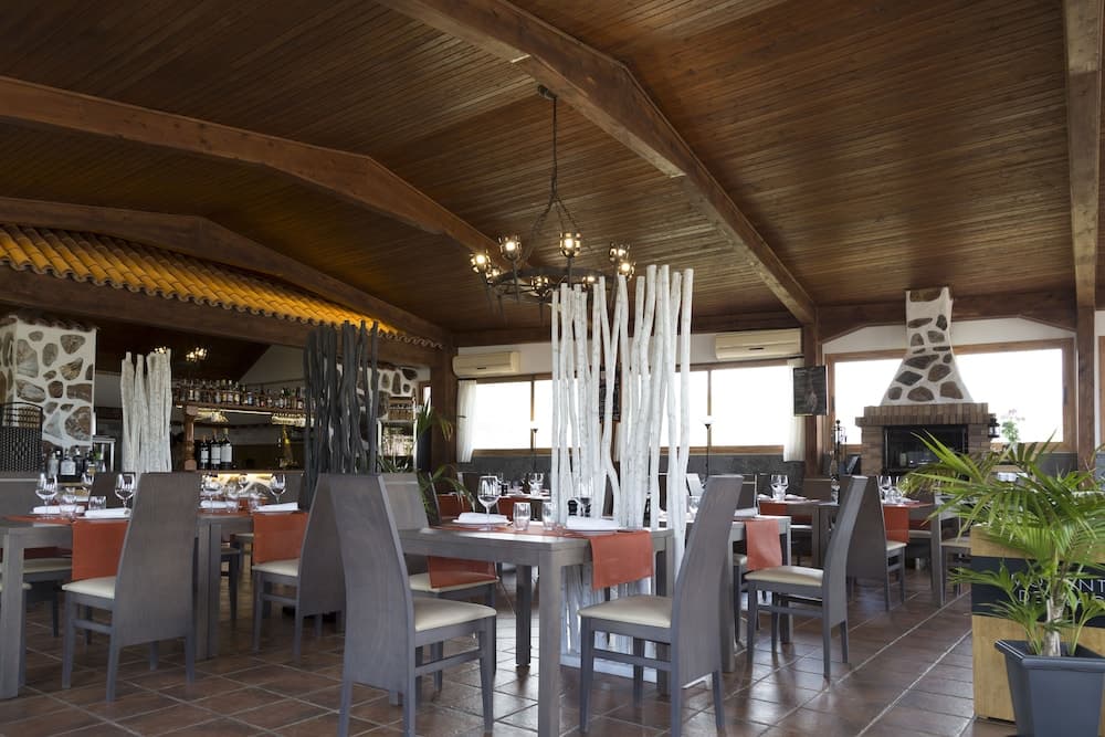 A cozy restaurant interior with wooden ceilings, rustic decor, and natural light filtering through large windows creates an inviting atmosphere perfect for travelers seeking a warm dining experience.