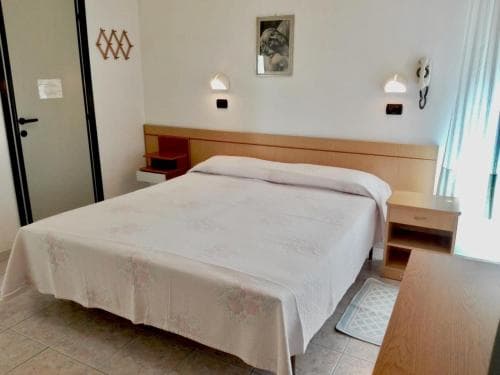 A cozy hotel room features a neatly made bed with floral bedding, wooden furniture, and soft lighting, creating a welcoming atmosphere ideal for travelers seeking comfort and relaxation.