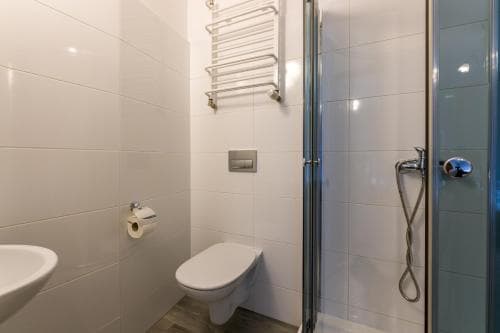 A modern, compact bathroom with white tiled walls, a sleek shower enclosure, and minimalist fixtures offers a clean and functional space ideal for travelers seeking efficient accommodations.