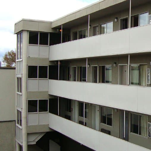 A multi-story residential building with balconies and large windows under an overcast sky, ideal for urban exploration or architectural photography.