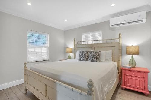 A cozy bedroom with a bamboo bedframe, coral nightstand, and soft lighting creates a serene retreat ideal for vacation rentals or home stays.
