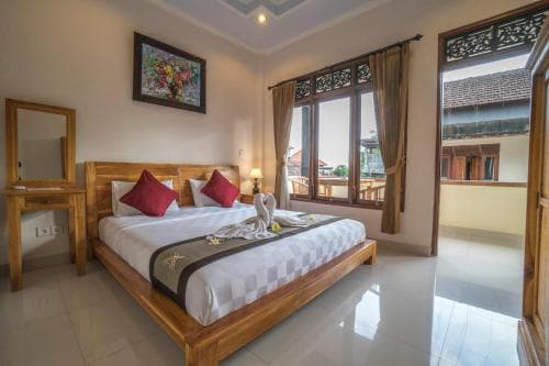 A cozy hotel room with a wooden bed, vibrant artwork, and a balcony view of traditional architecture, ideal for travelers seeking comfort and cultural immersion.