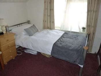 A cozy bedroom with a neatly made bed, patterned curtains, and soft lighting creates a serene atmosphere, ideal for travelers seeking a quiet and comfortable accommodation.