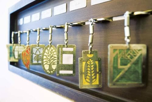 A neatly arranged display of intricately designed keychains on a wooden rack evokes a sense of craftsmanship and organization, ideal for travelers seeking unique souvenirs or gift shop enthusiasts.
