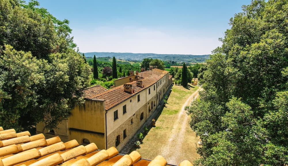 A serene countryside estate framed by lush greenery and terracotta rooftops offers an idyllic retreat for travelers seeking tranquility amidst nature.