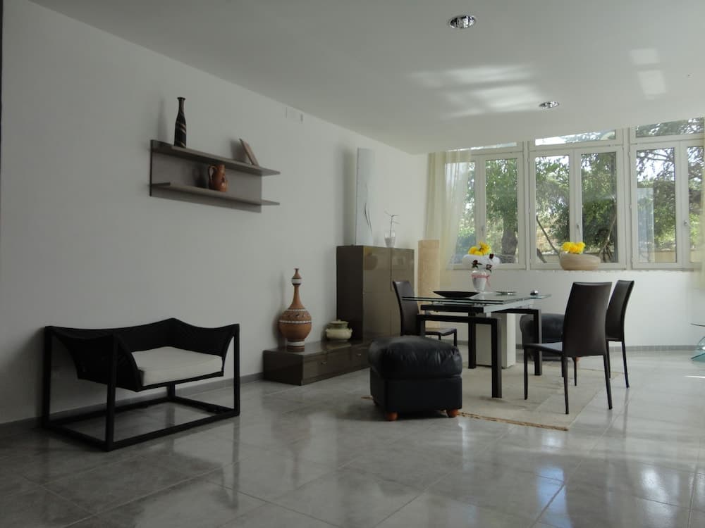 A serene modern living room with sleek furniture, decorative vases, and large windows inviting natural light, ideal for travelers seeking a tranquil accommodation space.