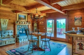 A cozy cabin interior featuring wooden walls, a rustic fireplace, and a vibrant rug creates a warm, inviting atmosphere perfect for a relaxing getaway, ideal for travelers seeking a serene retreat in nature.
