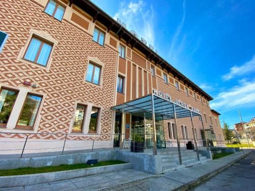 A charming hotel with a geometric-patterned facade stands under a vibrant blue sky, offering travelers a cozy retreat with modern amenities and a welcoming entrance.