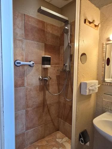 A cozy hotel bathroom features a tiled shower with modern fixtures, a sink, and a mirror, creating a functional and inviting space for travelers seeking comfort during their stay.