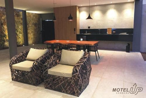 A cozy motel lounge features stylish wicker chairs with beige cushions, a wooden table, and modern lighting, creating a welcoming atmosphere ideal for travelers seeking relaxation.