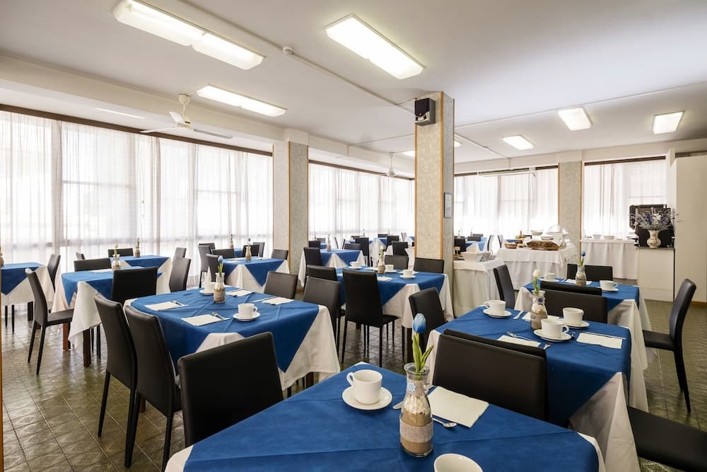 A well-lit dining hall with blue tablecloths, white chairs, and floral centerpieces offers a serene atmosphere ideal for group meals or business gatherings.