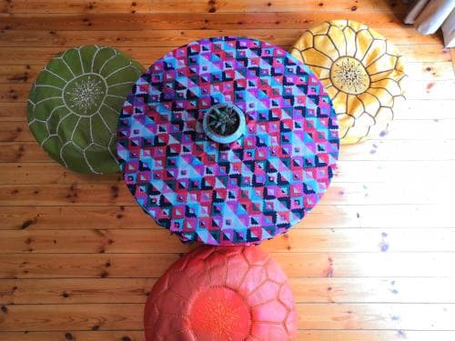 A cozy indoor space features vibrant, patterned ottomans on wooden flooring, ideal for a relaxing retreat or cultural exploration.