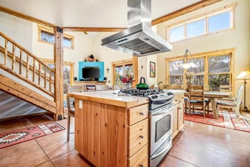 A cozy, rustic kitchen with wooden accents, a central island, and large windows inviting natural light, ideal for a family vacation rental experience.