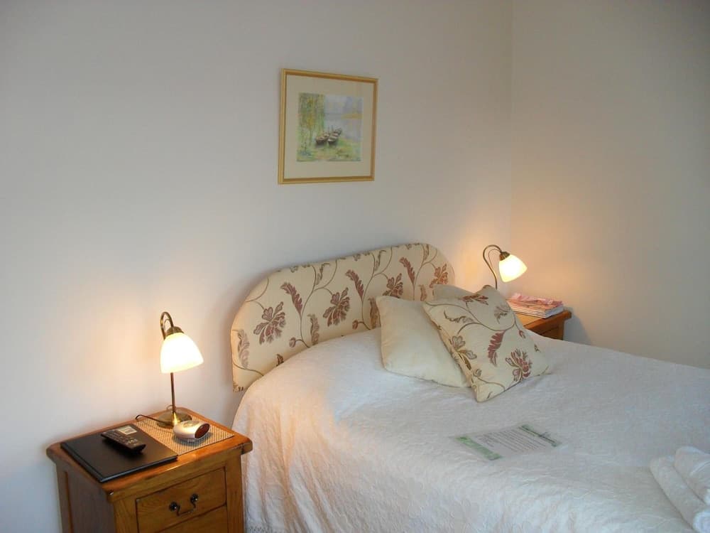 A cozy bedroom with a floral-patterned bed, warm bedside lamps, and a framed painting creates an inviting atmosphere ideal for travelers seeking relaxation.