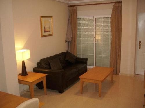 A cozy living room with a leather sofa, wooden tables, and soft lighting creates a warm atmosphere, ideal for travelers seeking a comfortable and inviting accommodation space.