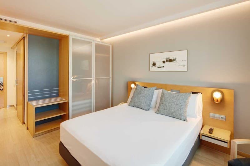 A cozy hotel room in Barcelona's Eixample district features modern furnishings, warm lighting, and a serene ambiance, ideal for travelers seeking comfort and style during their stay.
