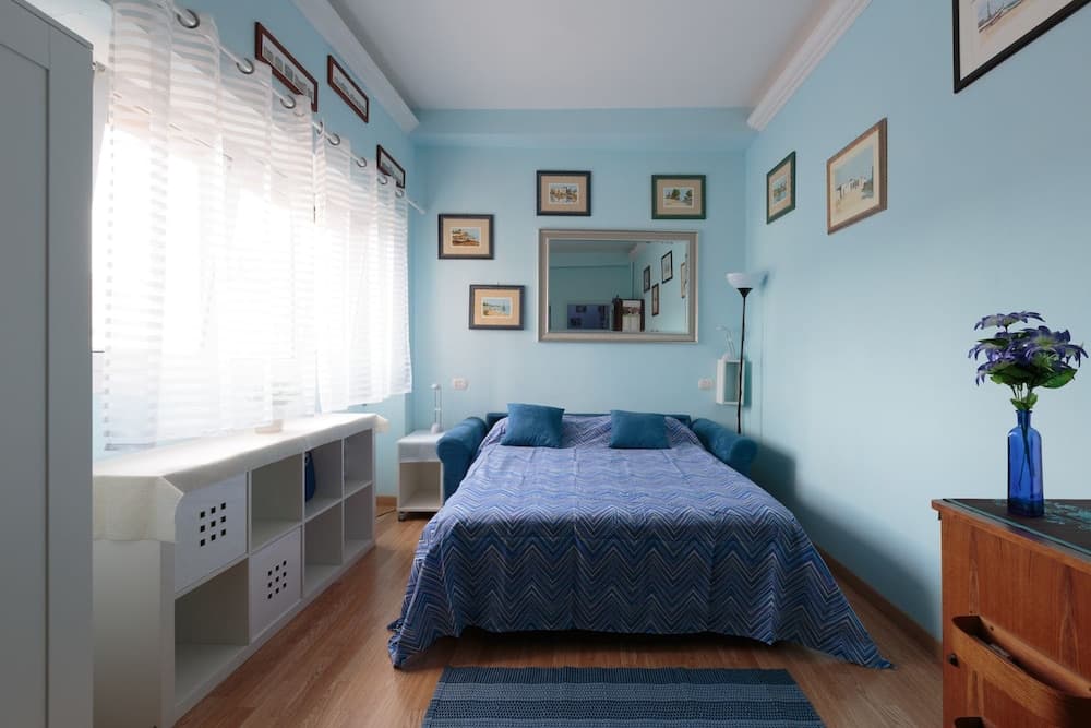 A serene bedroom with light blue walls, framed artwork, and a cozy bed invites travelers seeking a tranquil retreat, perfect for relaxation and restful sleep.