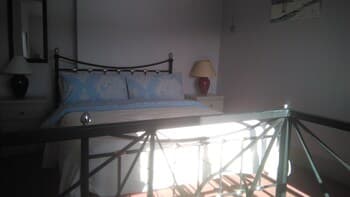 A cozy bedroom with a metal bed frame, soft blue bedding, and warm bedside lamps bathed in natural light creates an inviting atmosphere ideal for travelers seeking relaxation and comfort.