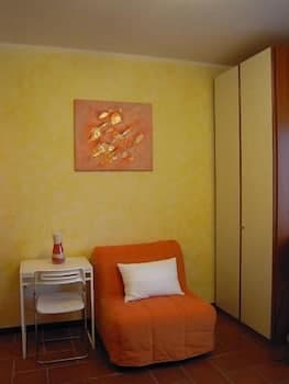 A cozy corner in a warmly lit room features an orange armchair with a white pillow, a small desk with a chair, and a vibrant abstract painting on the wall, ideal for travelers seeking a comfortable and artistic retreat space.