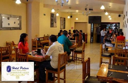 A cozy indoor restaurant with warm lighting, wooden furniture, and patrons dining creates an inviting atmosphere, ideal for travelers seeking a comfortable dining experience.