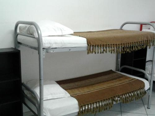 A cozy hostel room features bunk beds adorned with fringed blankets, creating a simple yet inviting atmosphere ideal for budget travelers seeking comfortable accommodations.