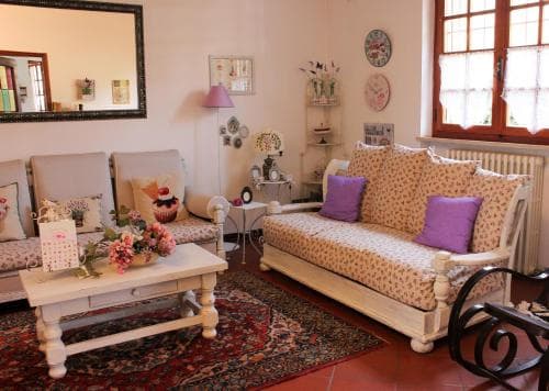 A cozy living room with vintage furniture, floral-patterned sofas, a wooden coffee table adorned with flowers, and a warm rug creates an inviting atmosphere perfect for a relaxing getaway or a charming Airbnb stay.