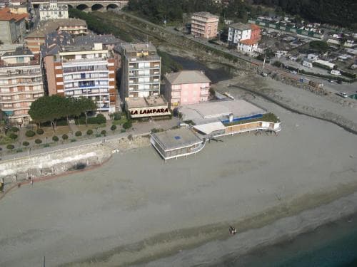An aerial view of a serene coastal town with sandy beaches, colorful buildings, and a waterfront promenade, ideal for travelers seeking relaxation and scenic beauty.