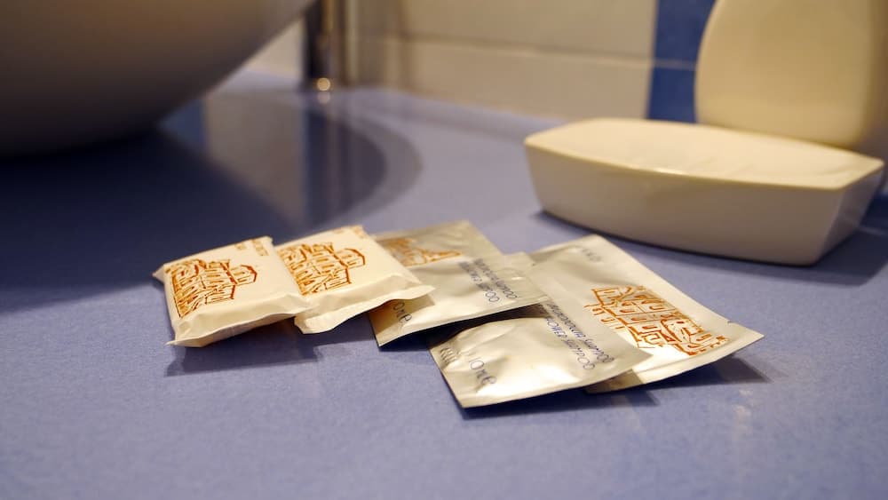A serene hotel bathroom scene features neatly arranged toiletry packets on a blue countertop, ideal for travelers seeking comfort and convenience during their stay.