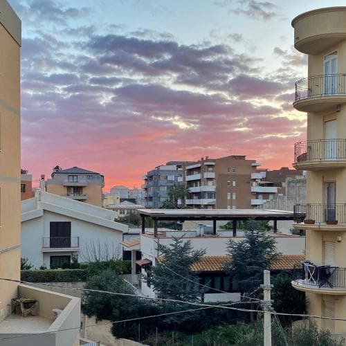 A serene sunset casts warm hues over a residential neighborhood with balconies and greenery, ideal for travelers seeking a peaceful urban retreat.
