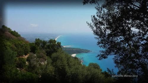 A serene coastal vista framed by lush greenery offers a breathtaking view of turquoise waters and sandy beaches, ideal for tranquil getaways and nature photography.