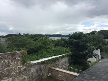 A serene view of lush greenery and distant hills from atop a historic stone wall, ideal for tranquil walks and nature photography.