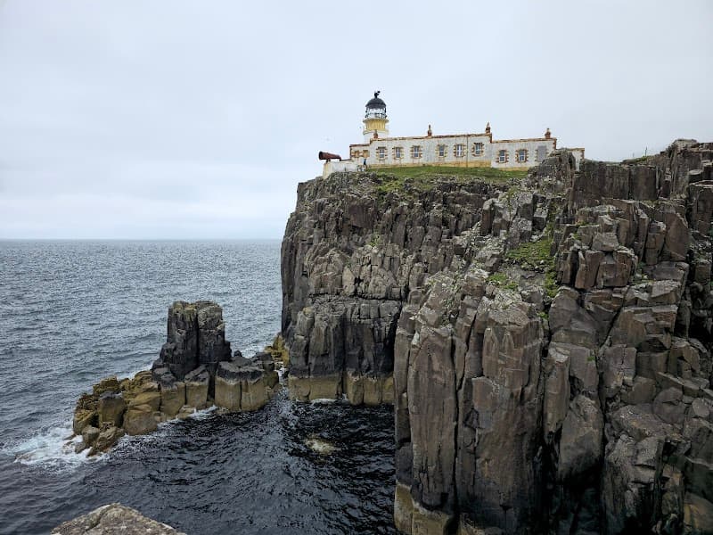 A serene coastal scene features the Neist Point Lighthouse perched atop rugged cliffs overlooking the vast ocean, ideal for travelers seeking picturesque landscapes and historic landmarks in Scotland's Isle of Skye.