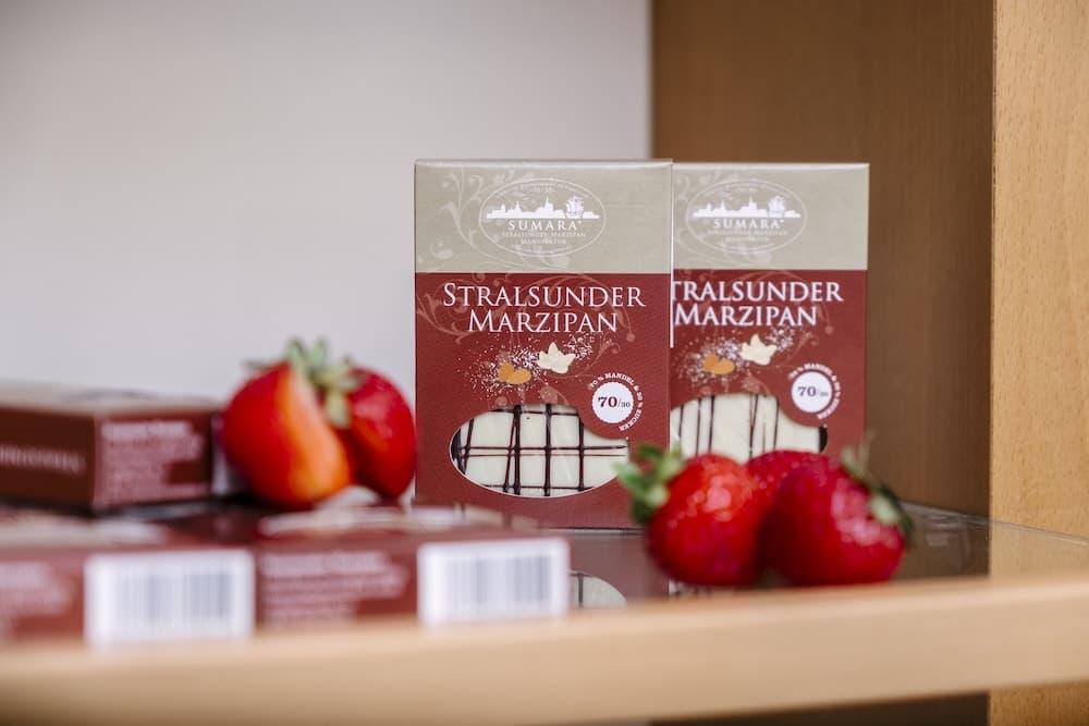 A cozy display of Stralsunder Marzipan boxes adorned with strawberries evokes a sweet and inviting atmosphere, perfect for travelers seeking local delicacies in a charming shop setting.