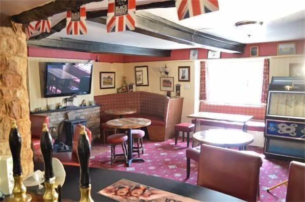 A cozy British pub interior features Union Jack flags, wooden beams, and vintage decor, creating a nostalgic atmosphere ideal for travelers seeking authentic local experiences.