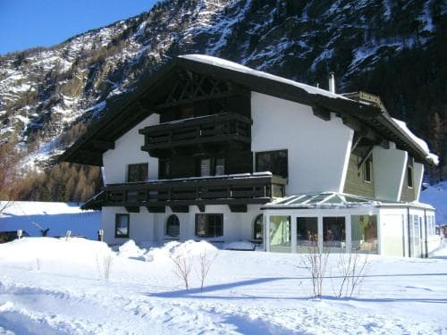 A cozy alpine chalet nestled in a snowy mountain landscape offers a serene winter retreat, ideal for skiers and snow enthusiasts seeking a picturesque getaway.