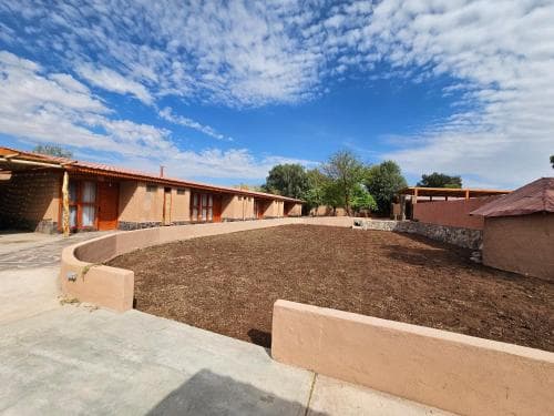 A serene courtyard with adobe buildings under a vibrant blue sky offers a tranquil retreat, ideal for travelers seeking cultural immersion in a rustic setting.