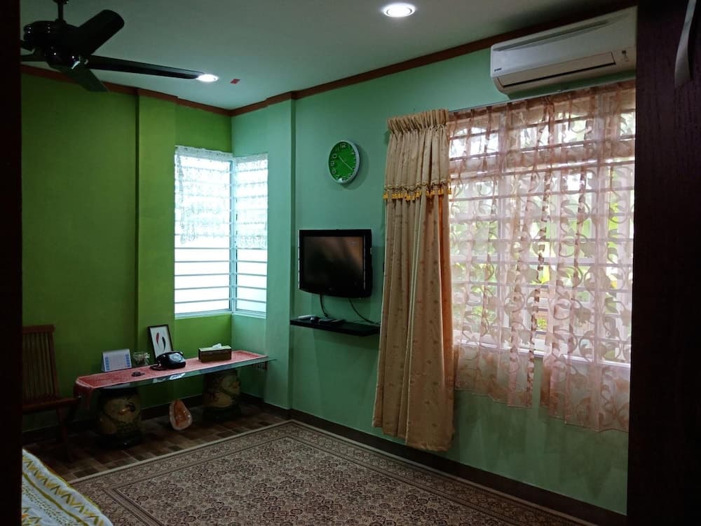 A cozy living room with green walls, patterned curtains, and a mounted TV exudes a relaxed atmosphere, ideal for travelers seeking a comfortable and homely accommodation.