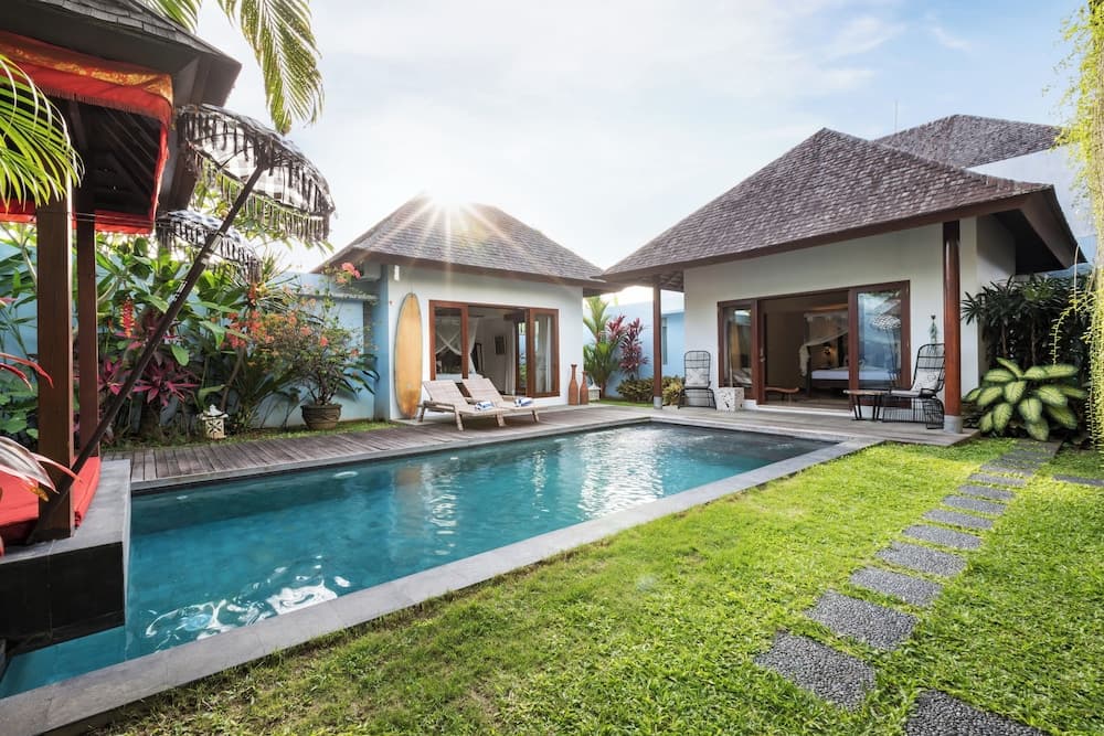 A serene tropical villa with a private pool, lush greenery, and traditional thatched roofs offers a tranquil retreat for luxury travelers seeking relaxation.