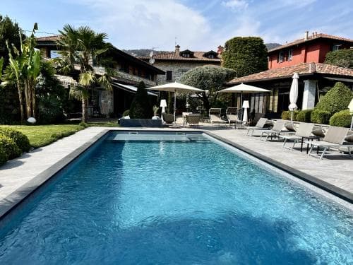 A serene luxury villa with a sparkling pool, lush greenery, and cozy lounge chairs invites travelers to unwind in a tranquil, upscale retreat setting.