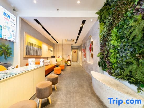A modern, inviting hotel lobby features a vibrant green living wall, cozy seating areas, and a reception desk adorned with travel brochures, ideal for travelers seeking comfort and relaxation during their stay.