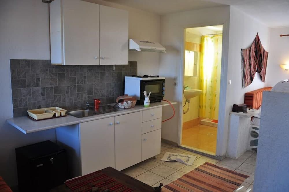 A cozy apartment kitchen with white cabinets, a tiled backsplash, and a view into a warmly lit bathroom, ideal for travelers seeking a homey and functional stay.