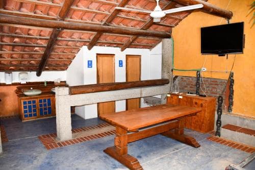 A rustic indoor space with wooden beams, tiled floors, and a long wooden table exudes a cozy, traditional atmosphere ideal for travelers seeking a unique cultural experience in a heritage setting.