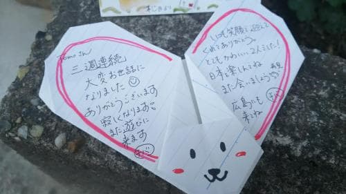 A serene park setting features a charming origami fortune teller with handwritten Japanese messages, ideal for cultural exploration and personal reflection during travel.