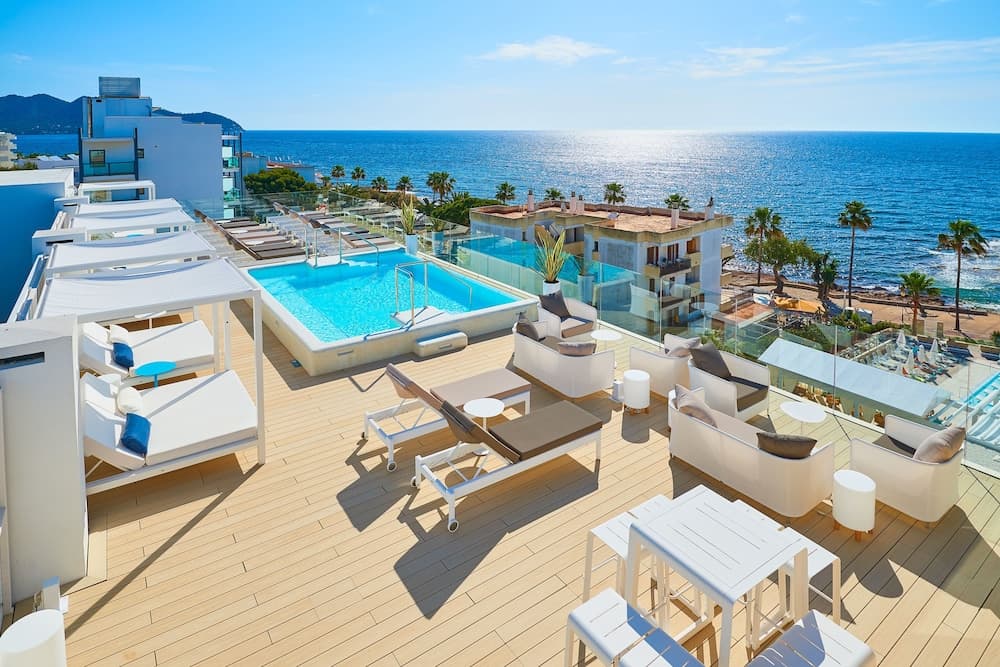 A serene rooftop terrace with lounge chairs, a sparkling pool, and panoramic ocean views offers an ideal spot for relaxation and luxury travel experiences.