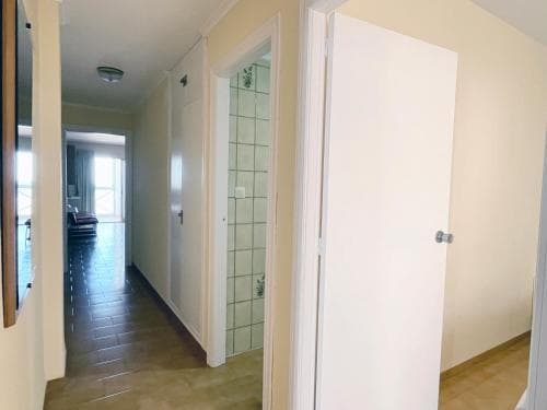 A cozy apartment hallway with tiled flooring, white doors, and a glimpse of a living area through an open doorway, ideal for travelers seeking comfortable short-term accommodations.