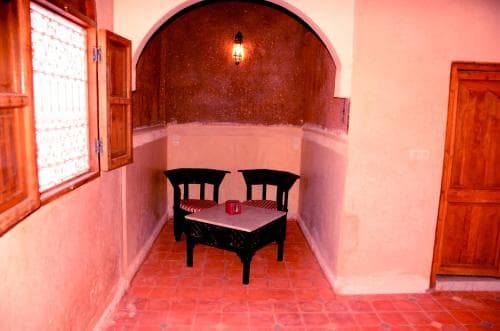A cozy, warmly lit indoor patio with terracotta tiles, wooden furniture, and a glowing lantern creates an inviting atmosphere perfect for a tranquil retreat or cultural exploration.