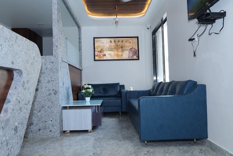 A cozy hotel lounge on the second floor features blue sofas, a modern desk with flowers, and a wall-mounted TV, creating a welcoming atmosphere ideal for travelers seeking comfort in Dwarka, Gujarat.